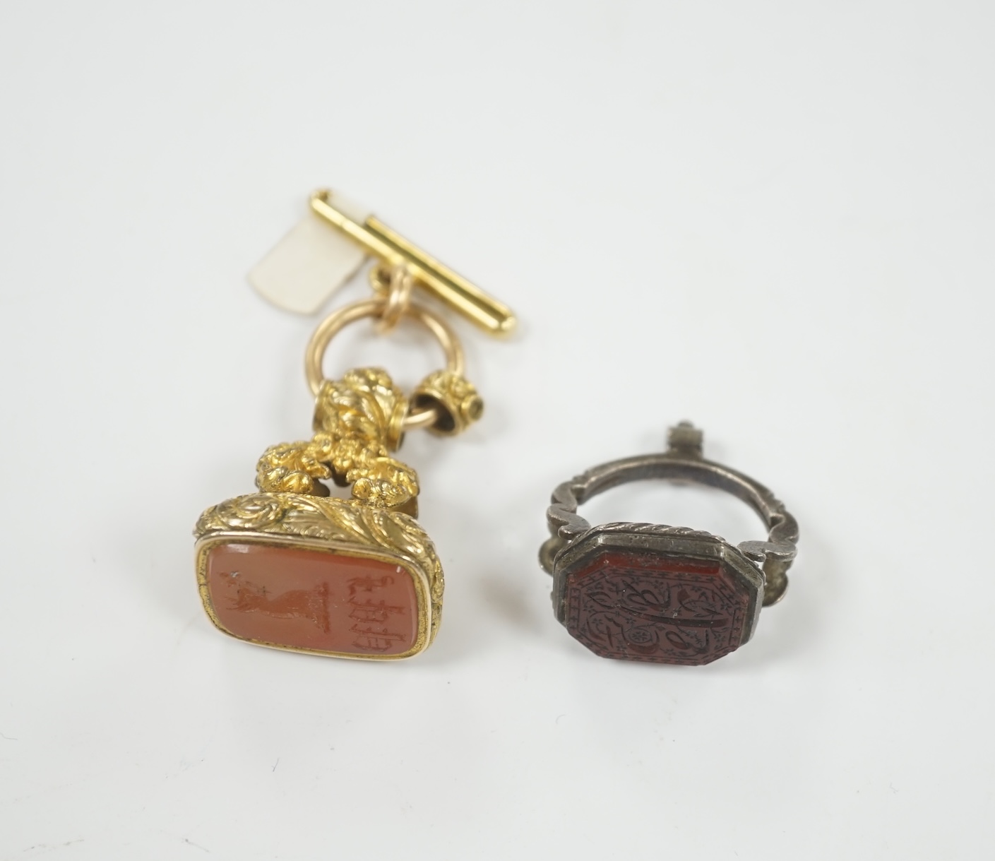 A 19th century gilt metal overlaid and carnelian set fob seal, 36mm, together with a white metal and chalcedony set fob seal, the matrix carved with Persian script.